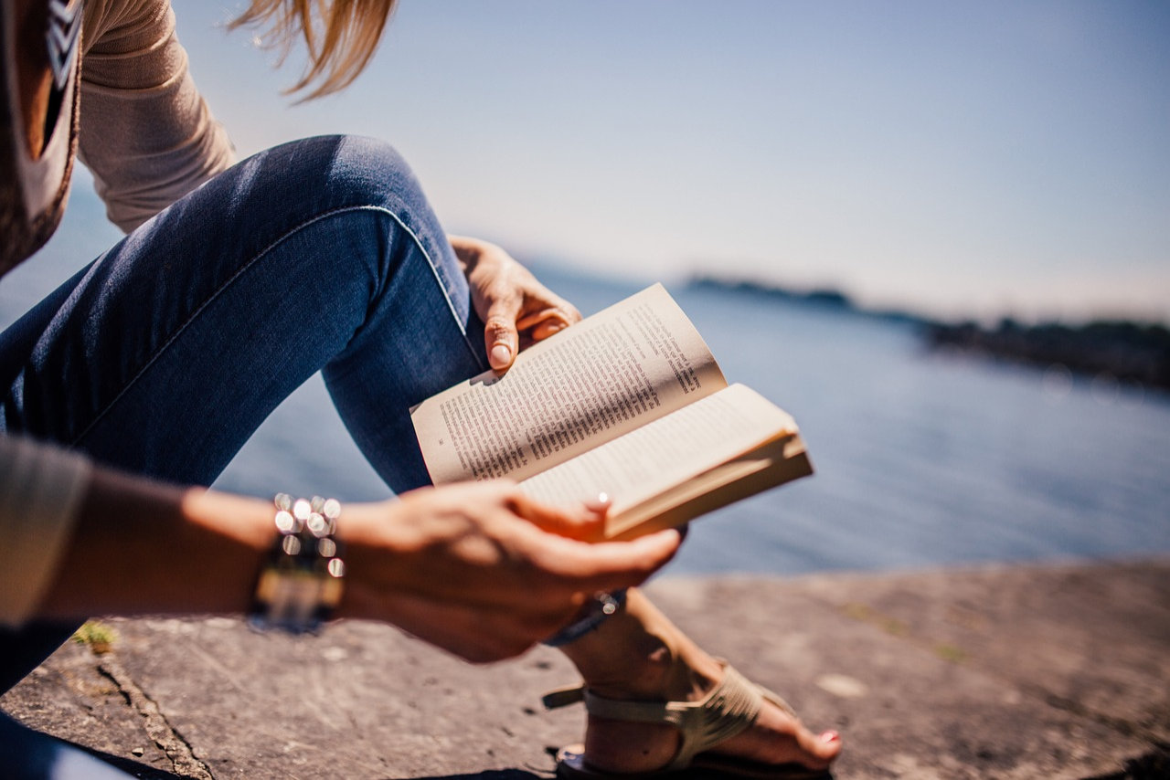 Woman reading a paperback novel on a beach